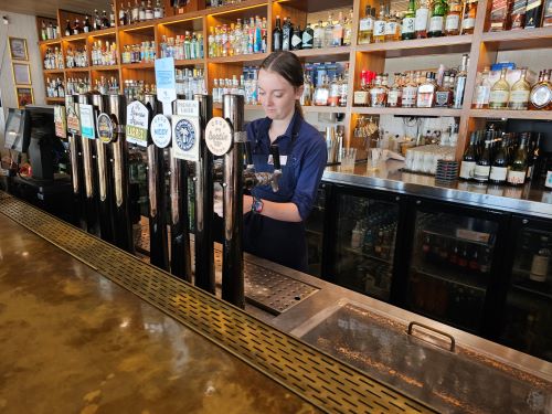 Ella pouring beers behind the bar at The Ville.